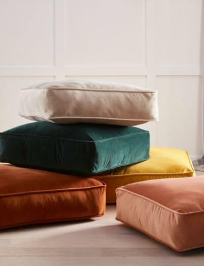 Photograph of a pile of colourful cushions on the floor.