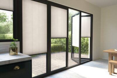 Photograph of large open glass doors with beige blinds over them.